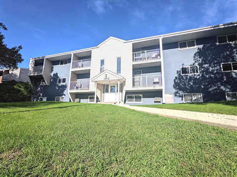 an exterior view of an apartment building with a green lawn